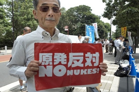 A man shows an anti nuclear placard at a rally to protest against re-operation of the nuclear power plant in front of the Nuclear Regulation Authority (NRA) in Tokyo on July 8, 2016.   Japan's Shikoku Electric Power Co. began loading nuclear fuel June 24 into Ikata 3 in preparation for a return to commercial operation in August. / AFP PHOTO / KAZUHIRO NOGI